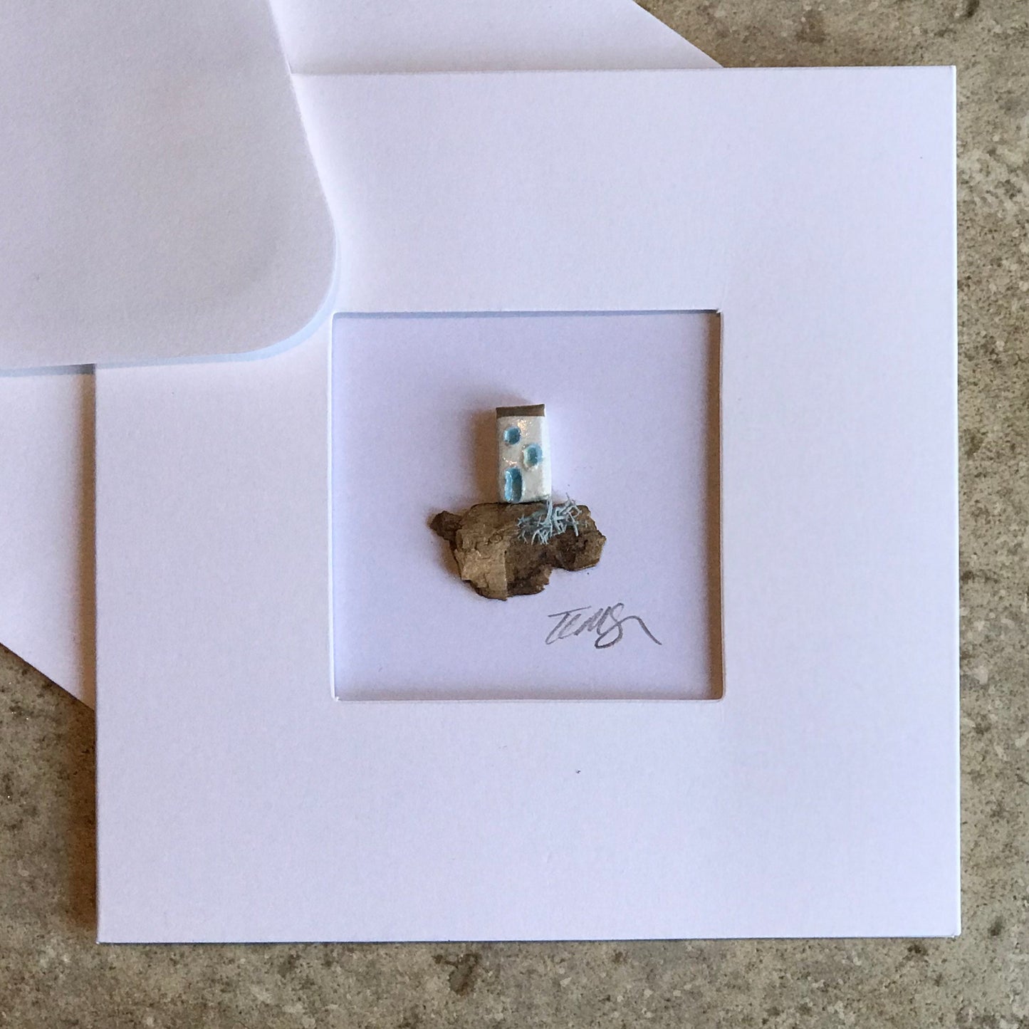 Little House card featuring a single handcrafted clay house on driftwood, framed in a 13.5 cm square aperture card.
