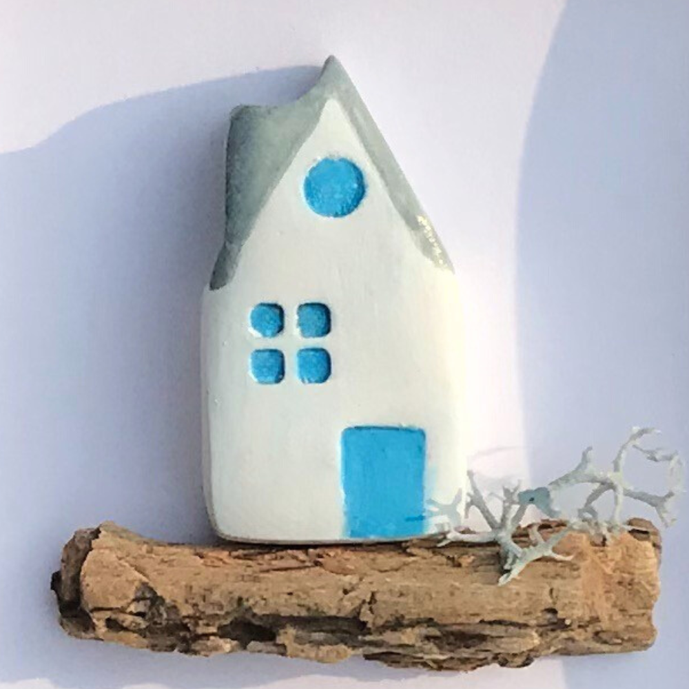 Close-up of Driftwood House design, featuring a white house with soft curves, blue windows, and natural driftwood.