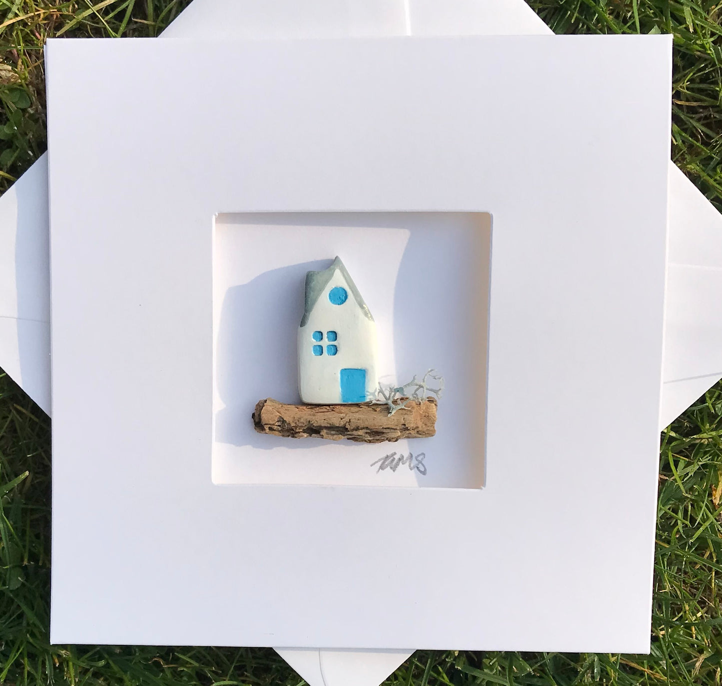 handcrafted coastal cottage art card with white and blue house on natural driftwood.
