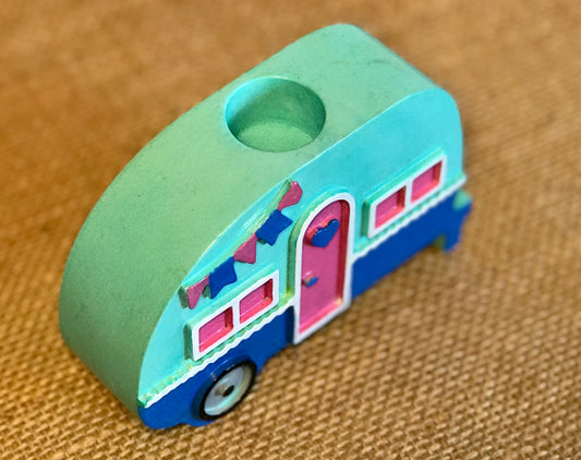 Side view of the ceramic campervan candle holder showing the recessed grey wheel detail and vibrant bunting accents under a glossy glaze