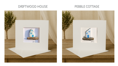 Two handmade coastal cottage cards side-by-side, each featuring a unique white and blue house design on natural driftwood.